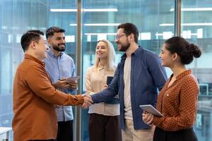 Diverse business team members shake hands in a modern office setting, symbolizing agreement and collaboration. photo