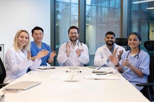 A diverse group of medical professionals applauds during a meeting, conveying teamwork and success. photo