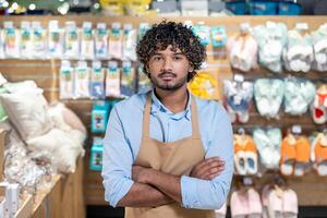 A confident store employee stands with arms crossed, showcasing the retail environment and a variety of products. photo