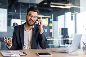 A young businessman talks on the phone while working in a modern office. photo
