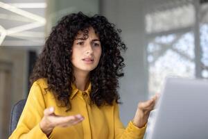 Serious and anxious woman talking to colleagues and partners sitting at desk with laptop, using call, for remote business conference meeting. photo
