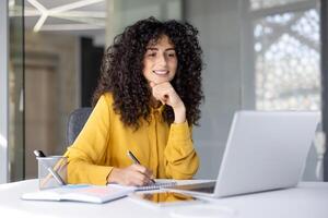 Businesswoman filling out tax forms online. Woman smiling and happy with paperwork inside office, working with contracts, documents and reports. photo