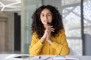 Smiling woman wearing a headset during a conference, seen from the first-person perspective, in a modern office setting photo