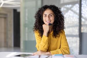 A friendly customer service representative smiles while working, showing her support and helpfulness for customers at their desk. photo