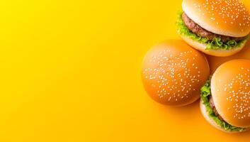 Yummy burgers on yellow. Two appetizing burgers topped with lettuce sit on a bright yellow background, showcasing a vibrant food presentation. photo