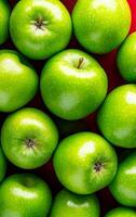 Vibrant green apple display. Shiny green apples are neatly arranged on a bold red background, showcasing their freshness and bright color. photo