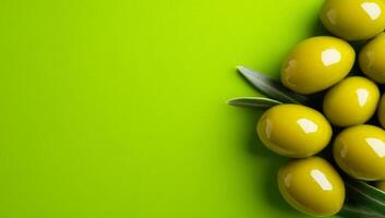Green olives on bright backdrop. Green olives are carefully arranged with olive leaves on a bright green surface, showcasing their glossy texture. photo