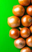 Onions on green backdrop. Shiny golden onions are arranged on a vibrant green surface, highlighting their smooth texture and rich color. photo