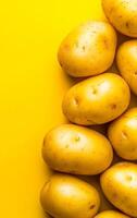 Golden potatoes on yellow bg. Fresh golden potatoes on a vivid yellow backdrop showcase their smooth texture and natural hue. photo