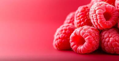 Raspberries on pink background. Juicy raspberries arranged in a mound on a vibrant pink surface, highlighting their rich color and texture. photo