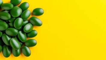 Green candies on yellow backdrop. A pile of shiny green candies rests on a bright yellow surface, creating a lively and colorful contrast. photo