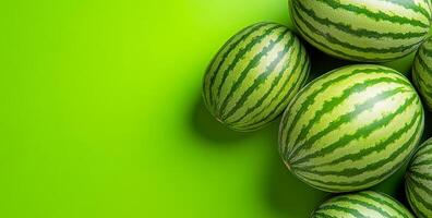 Watermelons on green bg. Several ripe watermelons are arranged on a vibrant green surface, showcasing their striped pattern and freshness. photo