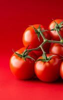 Fresh red tomatoes on vibrant background. A cluster of ripe red tomatoes is displayed against a bright red background, showcasing their freshness and shine. photo