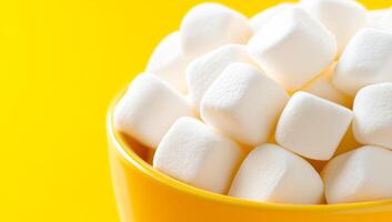 Marshmallows stacked in a yellow bowl. Soft white marshmallows are piled in a bright yellow bowl, creating a playful and inviting atmosphere in a cozy setting. photo