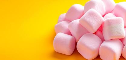 Colorful marshmallows displayed. Soft pink marshmallows stacked on a bright yellow background create a cheerful display. photo