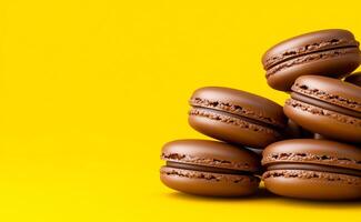 Chocolate macarons on yellow background. A stack of chocolate macarons rests against a vibrant yellow backdrop, showcasing their smooth texture and rich color. photo