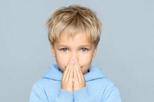 A Young Boy with a Cold Portrait of a Child Sneezing into a Tissue. Image Shows Symptoms of Illness, Emphasizing Healthcare and photo