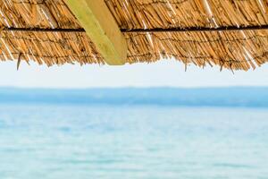 A tranquil and peaceful scene of a vibrant beach umbrella casting a relaxing shade on a sandy shoreline by the sparkling sea, creating a perfect coastal getaway on a sunny day. photo