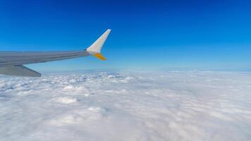 Stunning aerial view from an airplane window, featuring the aircraft s wing gliding above a sea of fluffy white clouds set against a bright blue sky. Perfect for travel and exploration. photo