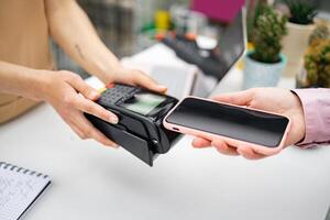 A customer makes a contactless payment at a florist shop using a smartphone device. photo