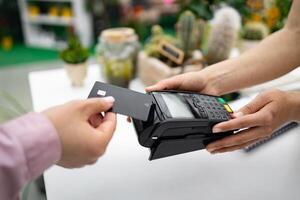 A person pays for purchases at a florist shop by using a credit card with a contactless payment terminal. photo