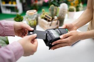 A customer is using a credit card to make a purchase at a florist shop, focusing on modern payment methods. photo