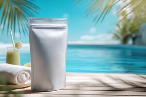 A white bag of sunscreen next to a towel and a drink photo