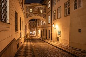 Illuminated by warm street lights, Thunovska Street showcases the charming architecture of the Chamber of Deputies and cobblestone pathways, creating a serene atmosphere at night in Lesser Town. photo