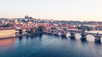 As dawn breaks over Prague, the golden hues illuminate the medieval architecture along the Vltava River, with the iconic Charles Bridge and Hradcany Castle in view, creating a breathtaking panorama. photo