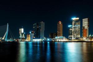 A mesmerizing night panorama of the city of Rotterdam, showcasing its modern high-rise architecture against a backdrop of a starry night sky, creating an enchanting and captivating urban landscape. photo