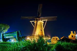 A serene night scene in Zierikzee, Netherlands, capturing the mesmerizing beauty of an old windmill adorned with enchanting lights, providing a captivating and tranquil atmosphere. photo