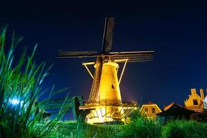 Beautiful old windmill standing tall and illuminated by colorful lights during the night in Zierikzee, a historic town in the Netherlands, creating a stunning and picturesque scene. photo