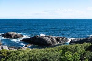 The deep blue Ocean with waves crashing on a rocky island. rugged, rocky coastline at the Sea photo