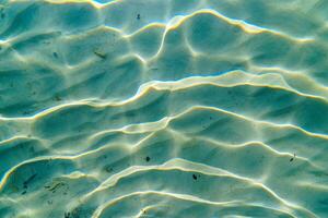 Underwater Sand Ripples with Sunlight Reflections, Ocean Floor Texture Abstract View photo