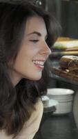 Joyful woman delightfully selecting desserts from a tempting bakery display video