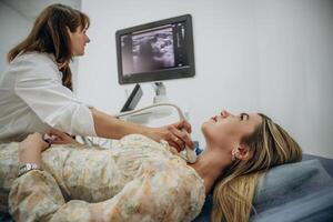 Woman, is lying down and undergoing ultrasonic test of the thyroid gland photo