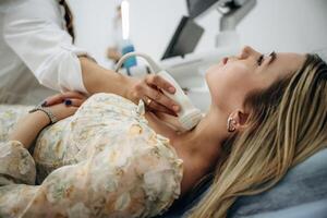 Side view.. Woman is lying down and undergoing ultrasonic test of the thyroid gland photo