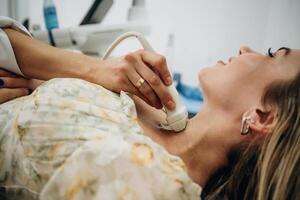 Side, view. Woman is lying down and undergoing ultrasonic test of the thyroid gland photo