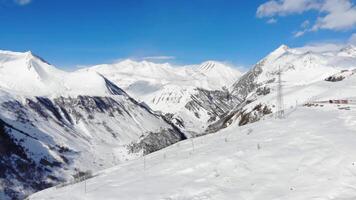 Drone panoramic view of snowy alpine valley with mountains and power lines. Pristine winter scenery, nature, energy infrastructure, cold climate. video