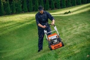 Process of ,cutting ,the grass by using lawn mover. Professional gardener is on the lawn photo