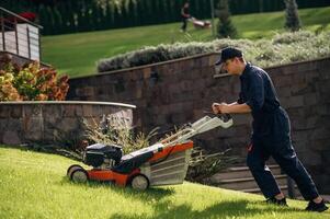 View ,from ,,the side, cutting grass by lawn mover. Professional gardener is on the lawn photo