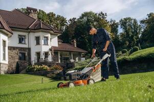 Cutting ,the, grass by lawn mover. Professional gardener is on the lawn photo