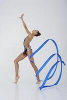 a girl from rhythmic gymnastics in a standing bodysuit shows an exercise with a ribbon photo