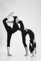 two girls from rhythmic gymnastics in a bodysuit show stretching and bending while standing photo