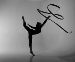 a girl from rhythmic gymnastics in bodysuit shows an exercise with a ribbon photo