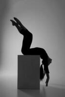 the silhouette of a girl from rhythmic gymnastics in a bodysuit on a cube in a deflection photo