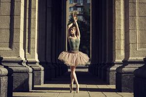 ballerina, in tutu and pointe shoes shows ballet elements, on the streets, on a summer day photo