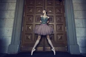 ballerina in tutu and pointe shoes shows ballet elements on the streets, on a summer day photo