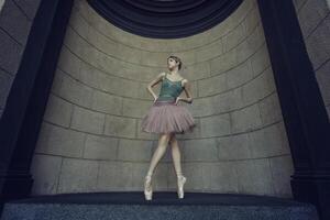 ballerina, in tutu and pointe shoes shows ballet elements on the streets, on a summer day photo