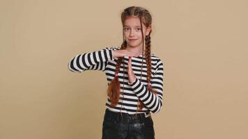Tired serious upset young preteen child girl kid showing time out gesture, limit or stop sign, no pressure, I need more time, take a break, relax, rest, help. Teenager children on beige background video